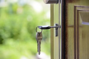 Clés suspendues à la poignée d'une porte en bois, symbole d'accès à une propriété. L'arrière-plan verdoyant suggère un cadre naturel paisible, idéal pour une maison à vendre dans la région de l'Outaouais.